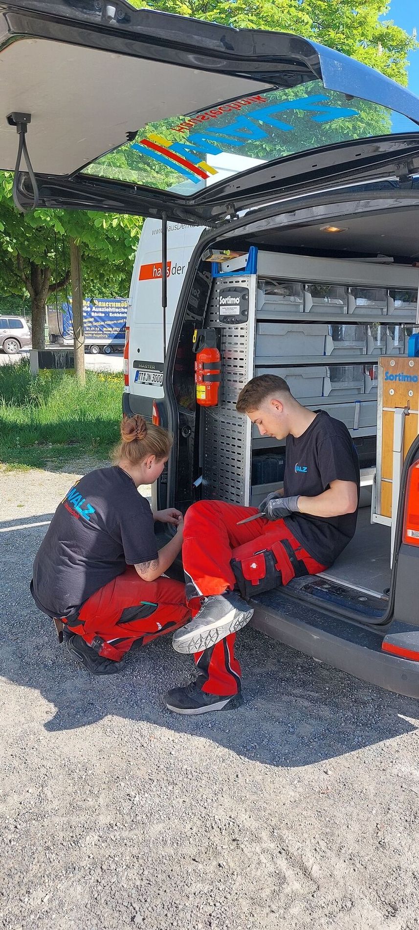 Zwei Mitarbeiter bei einem Firmenfahrzeug