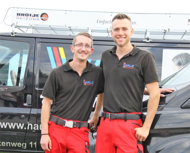 Zwei Mitarbeiter vor einem Firmenfahrzeug