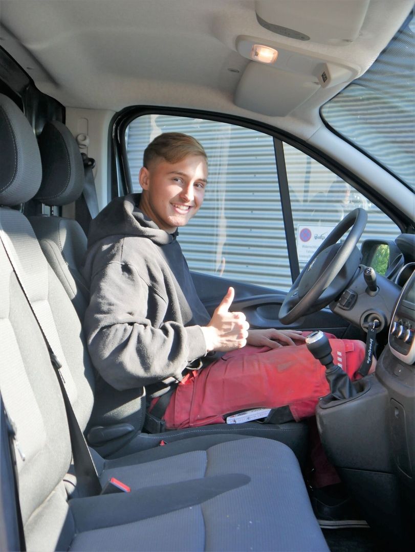 Ein Mitarbeiter sitzt in einem Firmenwagen und ist motiviert